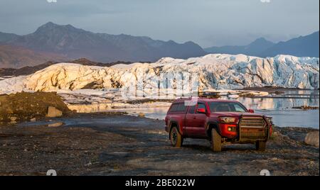 Red Pickup LKW Camper vor einem Gletschersee und Eisfall geparkt. Offroad-Fahren im abgelegenen Alaska. Stockfoto