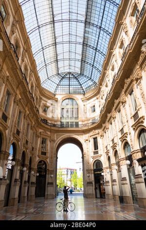 Leeres Denkmal: Galleria Vittorio Emanuele II in Mailand, Italien während der COVID-19 Epidemie mit Mann auf Fahrrad Shooting Foto. Das tägliche Leben in Milano Italia Stockfoto