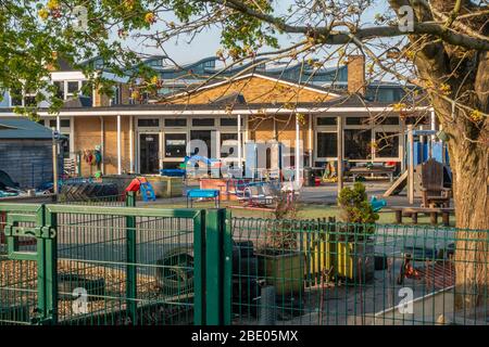 Bäume sprießen auf einem ruhigen, leeren Schulhof. Die Schule ist wegen der Coronavirus-Pandemie geschlossen. Das Tor ist verschlossen. Stockfoto