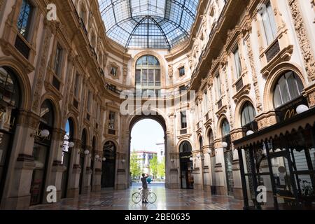 Verlassene Galleria Vittorio Emanuele II in Mailand, Italien während der COVID-19 Epidemie mit Mann auf dem Fahrrad fotografieren. Alltag in Mailand mit Coronavirus Stockfoto