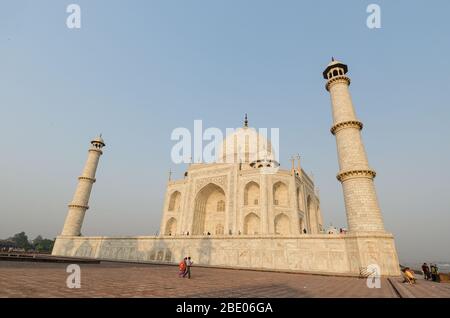 AGRA, INDIEN - 5. Mai 2015: Touristen spazieren durch das ikonische Mausoleum im Taj Mahal Komplex, beleuchtet von Sonnenaufgang, Agra, Indien Stockfoto