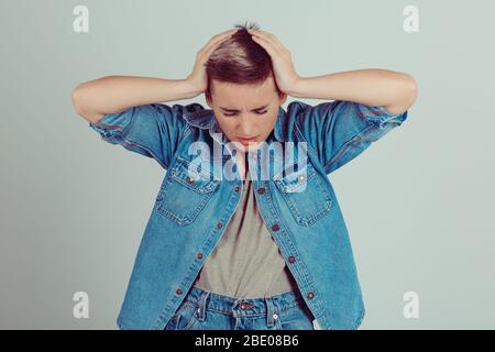 Attraktive Frau mit Kopfschmerzen auf grün grau hellen Hintergrund. Was habe ich gemacht Konzept Stockfoto