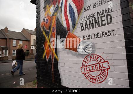 Eine Frau geht an einem Wandgemälde des defaced Orange Order im Osten von Belfast, 14. September 2005, vorbei. Orange Großmeister Robert Saulters sagte, der Orden betrachtete sich selbst als untadelig. Er verurteilte die Unruhen, beschuldigte aber die Polizei, "aggressiv und arrogant" zu sein. Er sagte, Gewalt nach dem Whiterock-marsch sei ein "Schrei der Verzweiflung" aus der protestantischen Gemeinschaft. Stockfoto