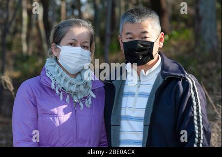 Ein Paar mittleren Alters, das eine Maske (weiße Maske und schwarze Maske) zum Schutz gegen Coronavirus COVID-19 (SARS-CoV-2) und andere Infektionskrankheiten trägt. Stockfoto