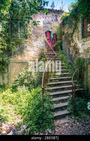 Alte eiserne verdrehte, überwachsene Treppe mit Graffiti an der alten Tür oben in Sintra bei Lissabon Portugal Stockfoto