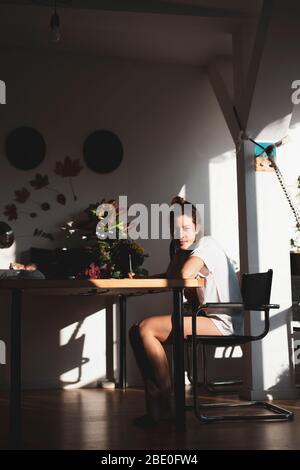 Schöne natürliche junge Frau sitzt und schreibt lächelnd in warmen Sonnenlicht Stockfoto