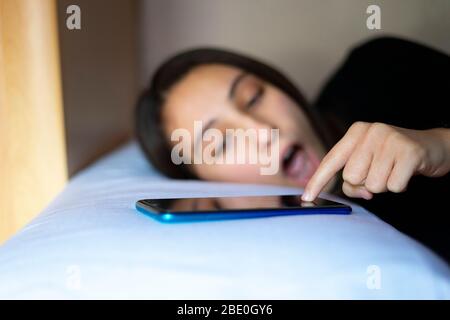 Eine frisch wach geworende Frau, die den Wecker abschaltet. Weckkonzept. Stockfoto