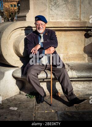 Älterer Mann mit einem spanischen Legion-Mützenabzeichen, der sich in der Sonne auf der Promenade Passeig de Lluís Companys, Barcelona, Spanien, entspannt. Stockfoto