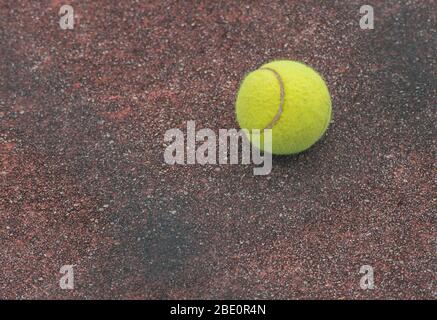 Ein gelber Tennisball auf Asphalt im Freien Stockfoto