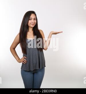 Eine hübsche Dame in Jeans hält ihre Hand heraus, während sie lächelt. Stockfoto