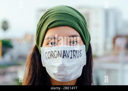 Mädchen mit Maske, um sich vor dem Coronavirus zu schützen. Covid-19-Pandemie. Coronavirus in Maske geschrieben Stockfoto