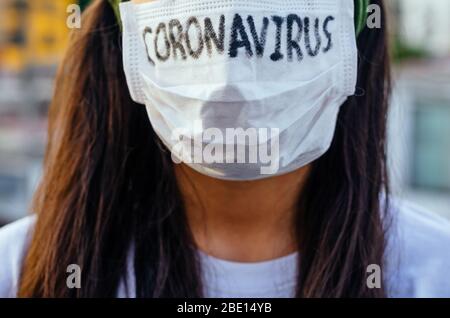 Junge Frau mit Gesichtsmaske und Coronavirus auf der Straße Stockfoto