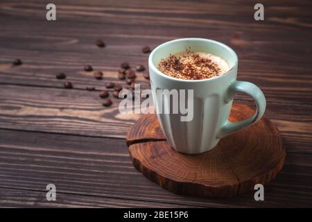 Tasse mit Kaffee auf einer ländlichen Holzplatte. Latte oder Cappuccino mit Schokoladenstreuseln. Kopierraum. Stockfoto