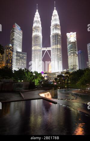 Am frühen Abend Foto der Petronas Towers in Kuala Lumpur, Malaysia mit Reflexion in einem kleinen Springbrunnen Pool. Stockfoto