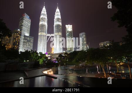 Am frühen Abend Foto der Petronas Towers in Kuala Lumpur, Malaysia mit Reflexion in einem kleinen Springbrunnen Pool. Stockfoto