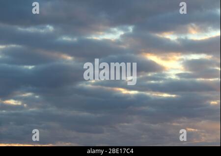 Die Sonnenstrahlen durchziehen die dunklen Wolken. Wunderschöner dramatischer Himmel bei Sonnenuntergang oder Sonnenaufgang. Stockfoto