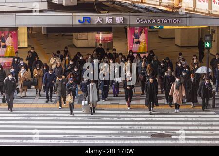 Osaka, Japan - 4. März 2020: Kleine Menschenmenge, die die Straße am normalerweise belebten Bahnhof in der Innenstadt überquert Stockfoto