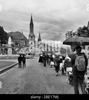 Menschen im Rollstuhl, die zum Heiligtum unserer Lieben Frau von Lourdes in der Hoffnung auf Trost oder Heilung ihrer Krankheiten, Lourdes, Hautes-Pyrénées gerollt werden Stockfoto