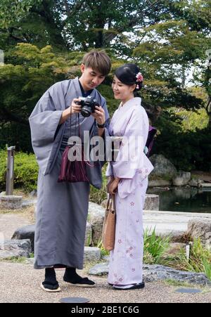 Kyoto, Japan - 30. September 2015: Junges Paar in schönem Kimono gekleidet, das Bilder vor der Kamera im Maruyama Park betrachtet Stockfoto