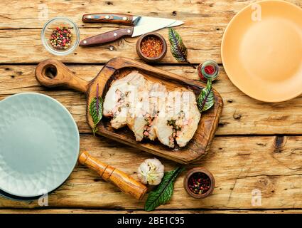 Schmackhaftes Lendenfleisch mit Sauerampfer und Speck gefüllt.gekochtes Schweinefleisch Lende auf rustikalem Tisch Stockfoto