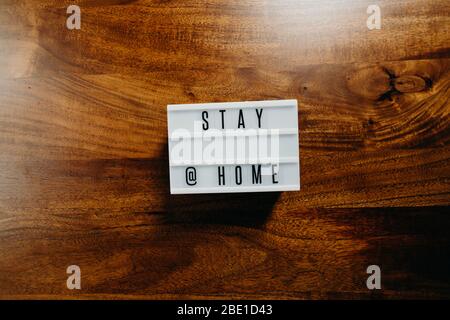 'Stay @Home' Text in Leuchtkasten auf Holzhintergrund. Stockfoto