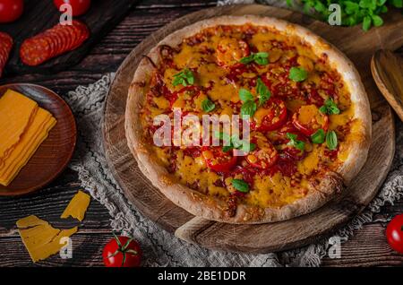 Rustikale hausgemachte Pizza mit scharfem Cheddar Chesse und würziger Salami Stockfoto