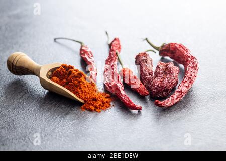 Getrocknete rote Chilischoten und Chilipulver in Holzschaufel würzen. Stockfoto