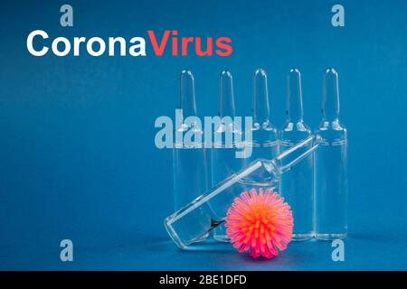 Abstraktes Modell des Coronavirus und Ampulle mit Medizin auf blauem Hintergrund. Das Wort Coronavirus wird geschrieben. Coronavirus stoppen. Stockfoto