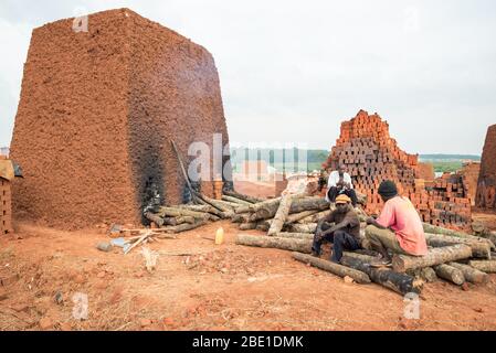 Kampala / Uganda - 20. September 2016: Schwarze Männer arbeiten in der Lehmziegelfabrik in der Hauptstadt Ugandas in der Nähe eines Backsteinofens Stockfoto