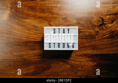 „Stay strong“ Text in Leuchtkasten auf Holzhintergrund. Stockfoto