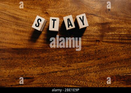 'Stay' Text aus Holzwürfel auf Holzhintergrund. Stockfoto