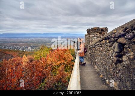 Touristische Paar auf der alten Stadtmauer mit Blick auf Alasani Valley im Herbst mal in Signagi, Georgien Stockfoto