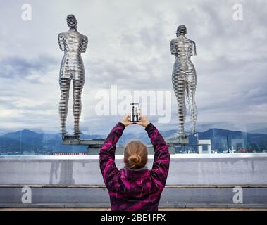 Touristische Frau heften Bild von Statuen Ali und Nino mit Smartphone in Batumi, Georgien Stockfoto