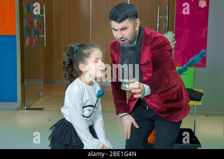 Ein Illusionist und Kinder halten eine Taube in den Händen. Der Magier zeigt eine Aufführung. Fokus-Illusionist zeigt Kinder Stockfoto