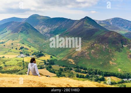 Ein Wanderer ruht auf Catbells im English Lake District und blickt über das Newlands Valley zu Fells einschließlich Grasmoor Causey Pike und Grisedale Pike Stockfoto