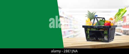 Warenkorb voll von Lebensmitteln auf Holztheke im Supermarkt Hintergrund Banner mit Kopierplatz für Text Stockfoto