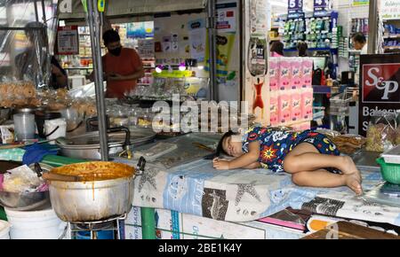 Bangkok, Thailand - 27. Februar 2020: Ein Kind, das auf einem der Verkaufsstände auf einem Nachtmarkt in Bangkok schläft. Stockfoto