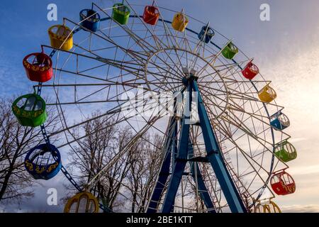 Riesenrad mit bunten Kabinen gegen den Himmel mit Wolken im Park an einem sonnigen Frühlingstag. Stockfoto