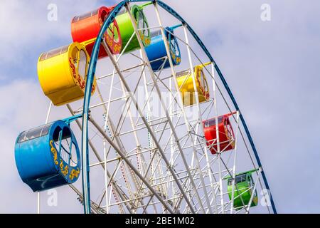 Riesenrad mit bunten Kabinen gegen den Himmel mit Wolken im Park an einem sonnigen Frühlingstag. Stockfoto