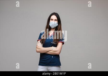 Professioneller Arzt in aseptischer Maske mit gefalteten Armen. Stockfoto