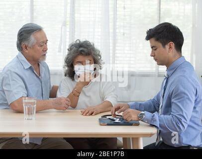 Ältere ältere ältere alte asiatische Paar Treffen Spezialist professionelle kaukasischen Arzt Besuch zu Hause Berater zwei Ruhestand Patient nach einer Untersuchung Stockfoto