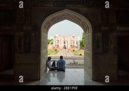 Agra, Indien - 4. Mai 2015: Zwei Männer sitzen im Schatten des Tumb-Mausoleums von I'timād-ud-Daulah in Agra, Indien Stockfoto