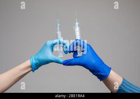 Zwei Hände in Handschuhen halten Spritzen Studio Schuss. Stockfoto