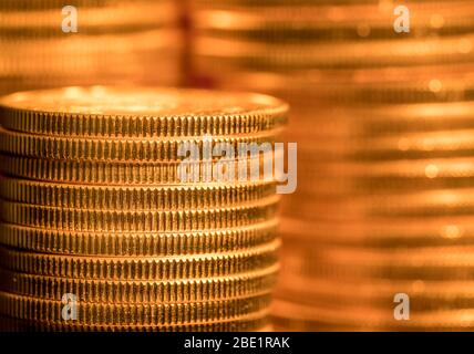 Konzentrieren Sie sich auf einen Stapel Goldmünzen, während andere Münzen im Hintergrund nicht fokussiert sind Stockfoto