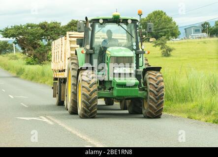 Afrikanischer Bauer fährt einen Traktoranhänger auf einer Straße in einer ländlichen landwirtschaftlichen Umgebung und Landschaft in Kwazulu Natal, Südafrika Stockfoto