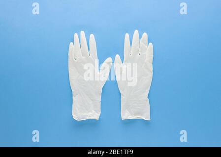 Neue saubere medizinische Gummihandschuhe zum Schutz der Hände vor Keimen auf hellblauem Hintergrund isoliert Stockfoto