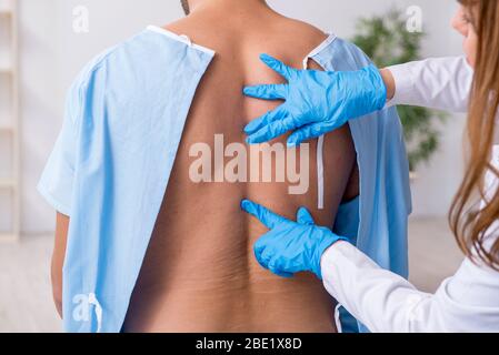 Junger verletzter Mann, der einen weiblichen Arzt aufsucht, Chiropraktiker Stockfoto