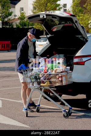 Tesco Supermarkt, Hove, Großbritannien, 2020. Ein älterer Mann entlädt seine Einkäufe mit einer Gesichtsmaske, um nach der Coronavirus-Pandemie sicher zu sein. Stockfoto