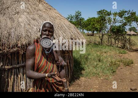 Frau der Mursi mit länglichen Unterlippe ein Ton Festplatte als Körper ornamentstribe Debub Omo Zone, Äthiopien zu halten. In der Nähe der sudanesischen Grenze. Stockfoto