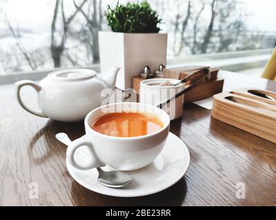 Zwei Tassen gesunder Kräutertee mit Meeresbuckthorn, Ingwer und Honig auf einem strukturierten, hellen Holztisch in einem Café mit modernem trendigen Interieur. Mockup für Stockfoto
